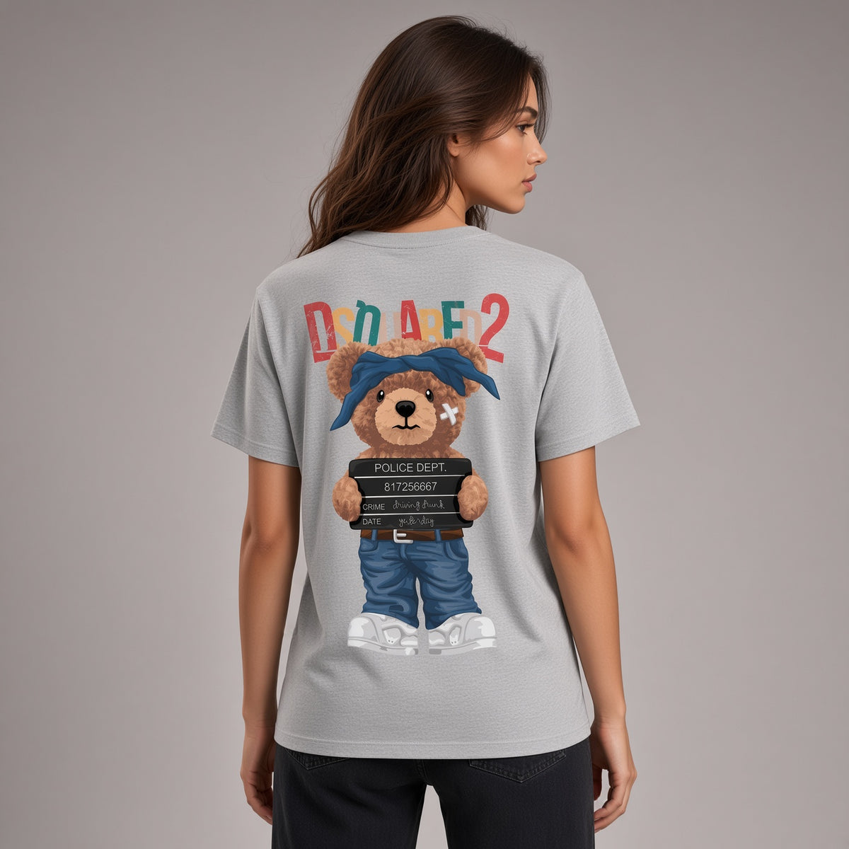 A woman shown from the back wearing a light gray t-shirt with a large graphic of a teddy bear dressed in a police outfit and the text 'DRAFE2' above it, set against a solid gray studio background.