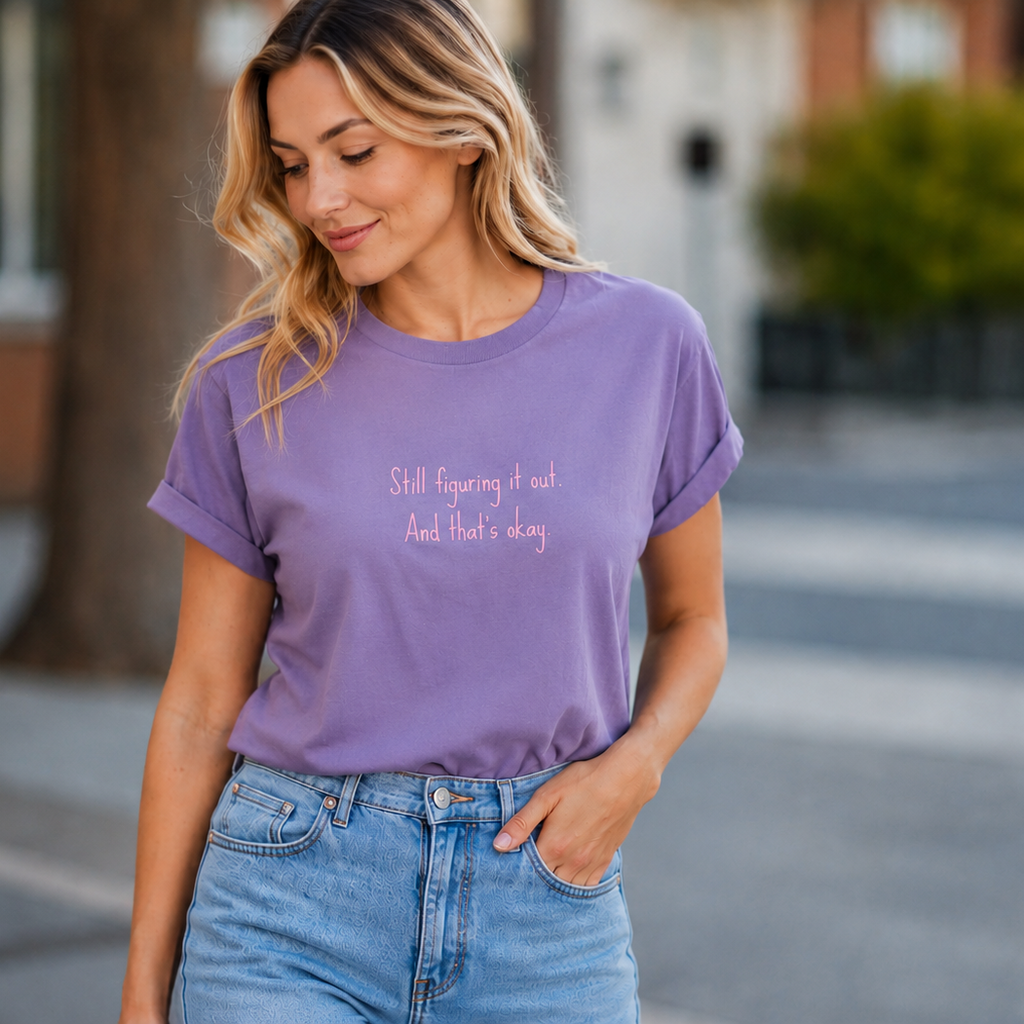 Woman wearing a purple t-shirt with text, standing outdoors.