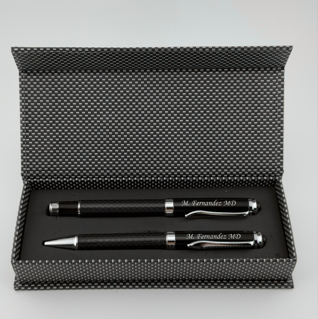 A black pen and ballpoint pen gift set in an open textured black presentation box, photographed on a light gray background.
