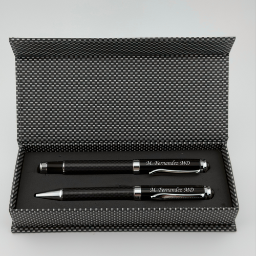 A black pen and ballpoint pen gift set in an open textured black presentation box, photographed on a light gray background.