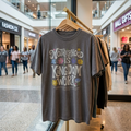Gray t-shirt with 'Motherhood is Kingdom Work' text in a shopping mall setting