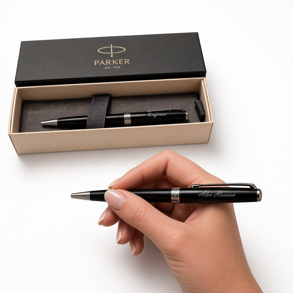 A hand holds a black Parker Signet pen with silver trim, positioned below an open black and beige Parker gift box containing another matching pen, on a clean white background.