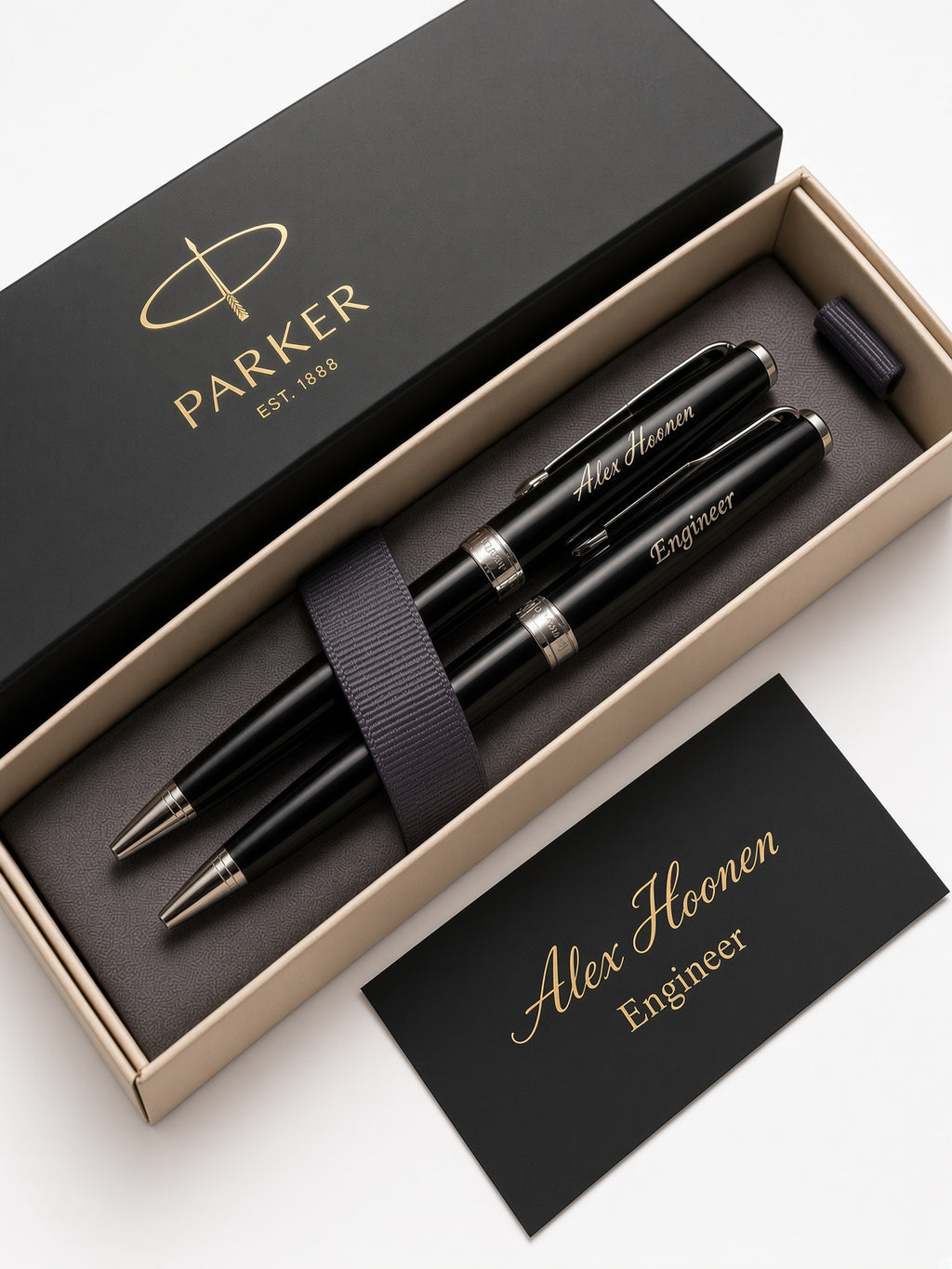 A personalized Parker pen set in an open beige presentation box, with a black branded lid, a black pen, a pen cap, and a black card reading 'Alex Hoonen Engineer' on a white background.