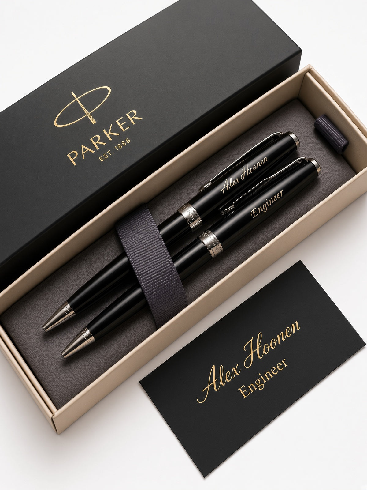 A personalized Parker pen set in an open beige presentation box, with a black branded lid, a black pen, a pen cap, and a black card reading 'Alex Hoonen Engineer' on a white background.