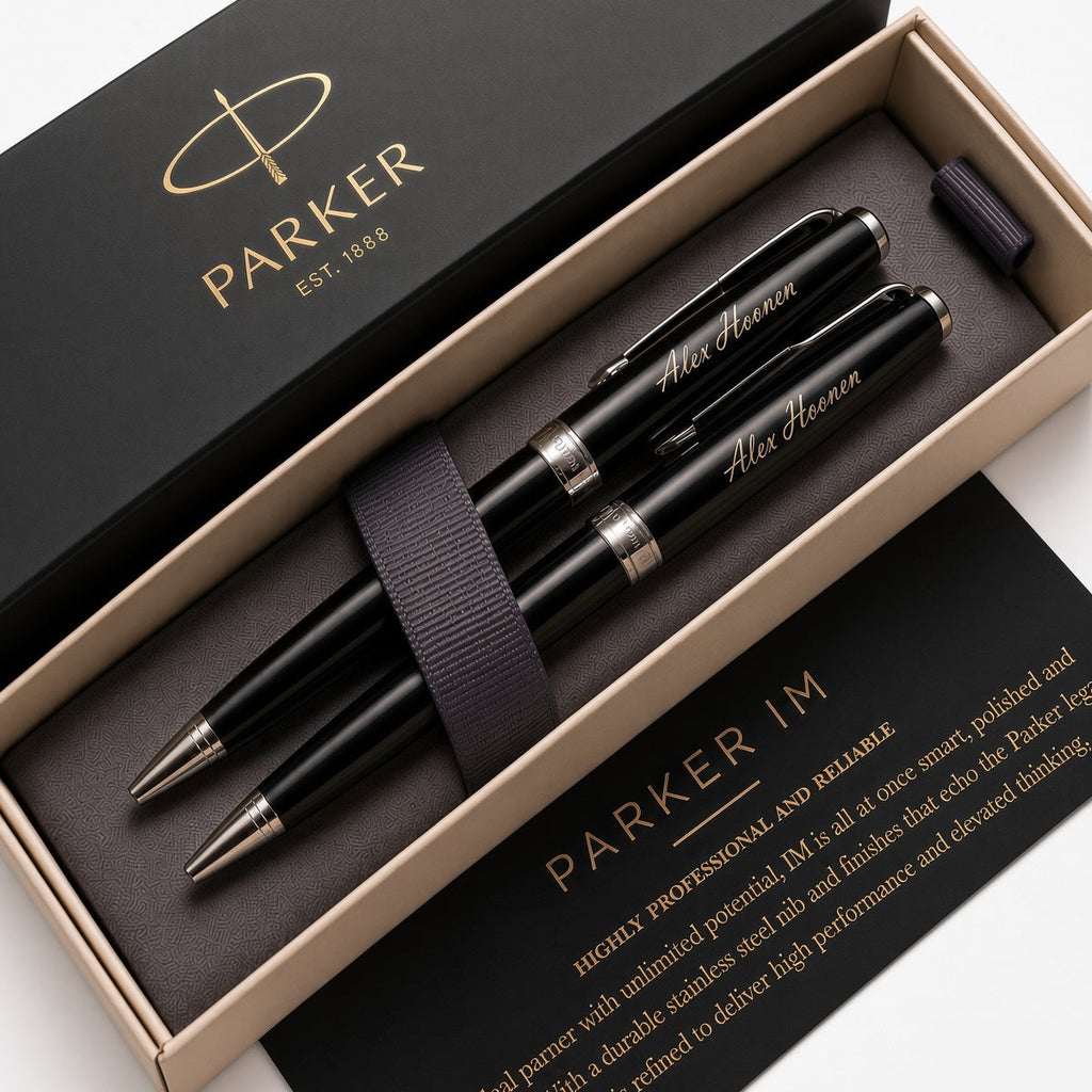 A Parker pen set in a black presentation box, featuring two black ballpoint pens with silver accents and gold-etched personal names, alongside a black ribbon and branded packaging.