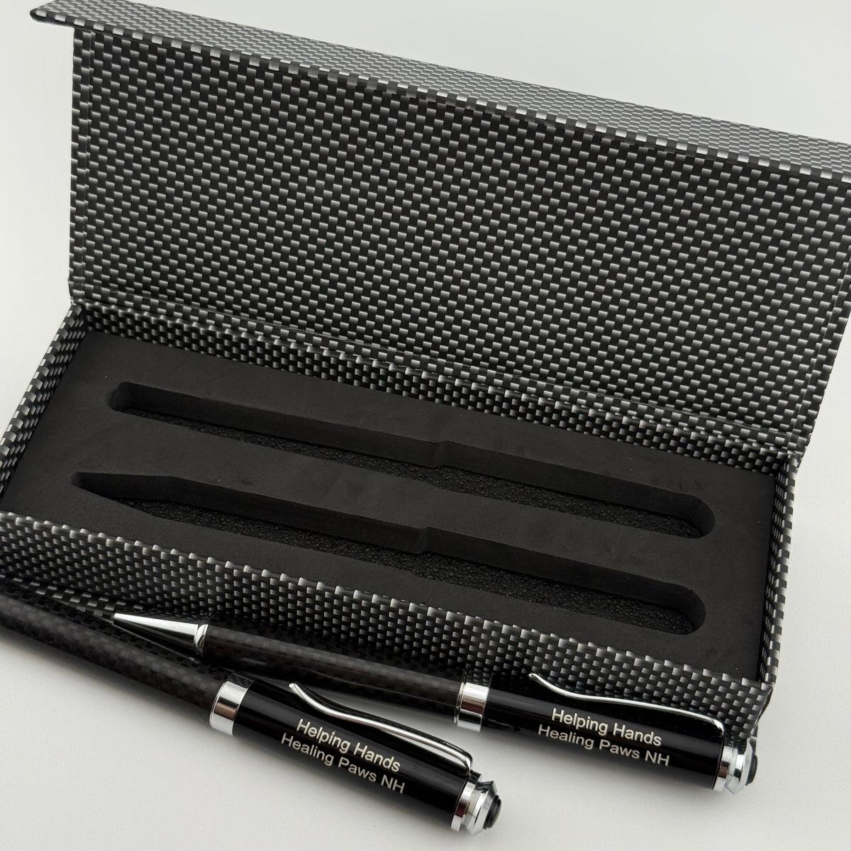 A black and silver pen and matching pencil set displayed in an open textured black presentation box on a light gray background.