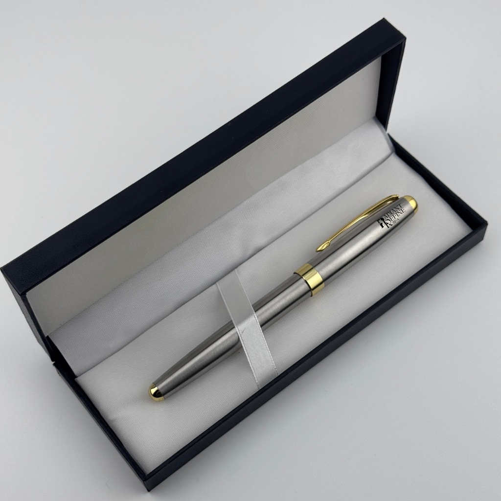 A silver metal ballpoint pen with gold trim and a gold pocket clip, presented inside an open black gift box with a white velvet lining on a light gray background.
