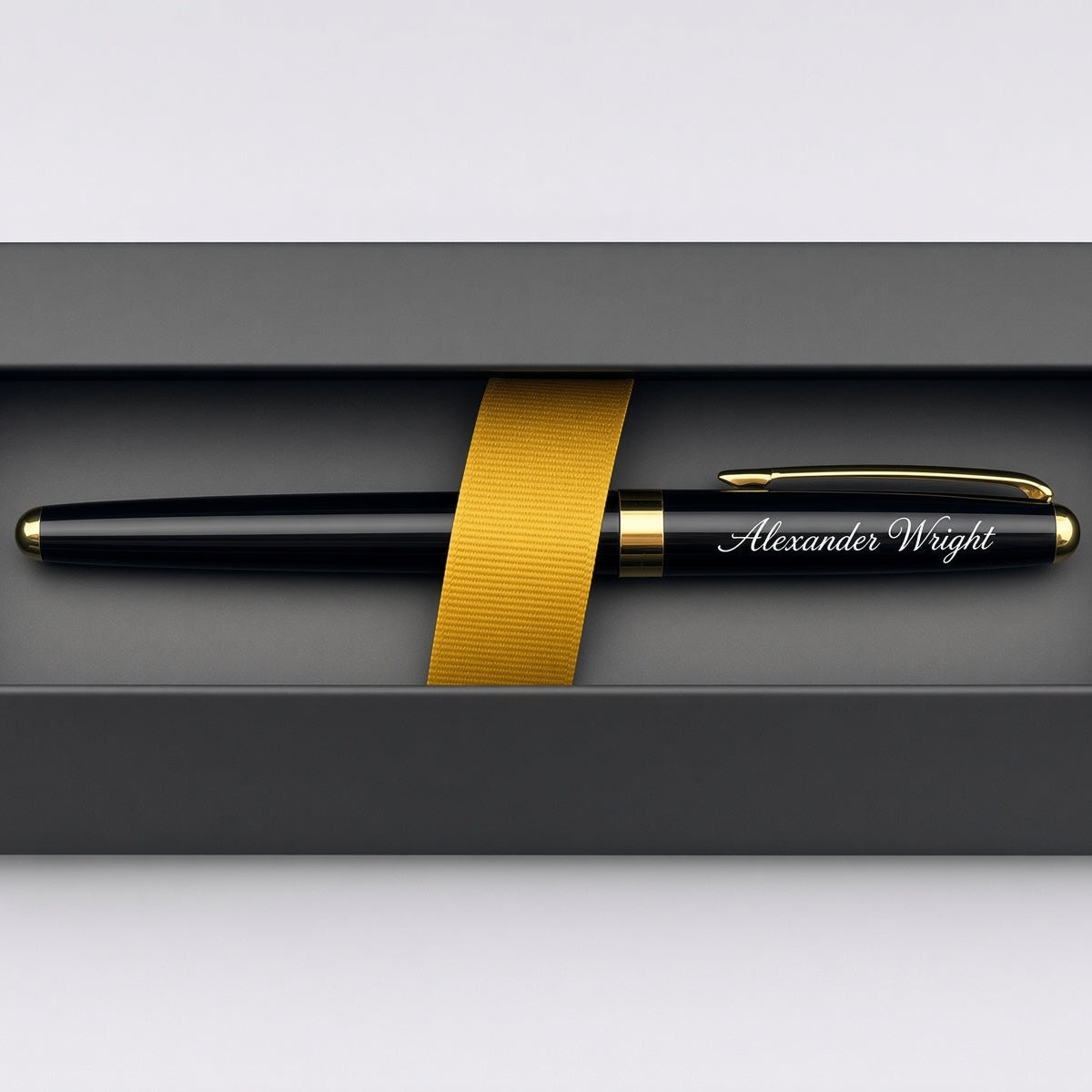 A personalized black pen with gold trim and the name 'Alexander Wright' engraved on the clip, presented inside a dark gray gift box with a gold ribbon.